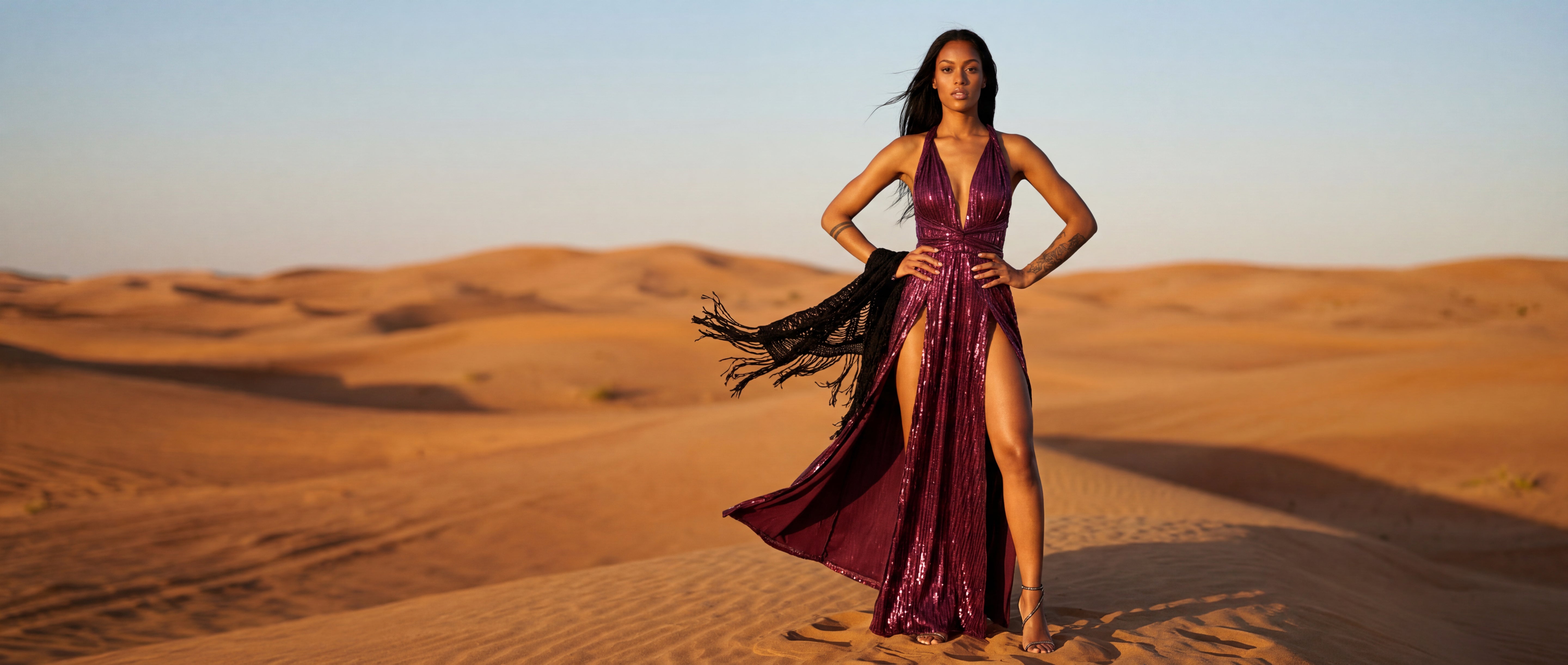 Woman in a purple dress standing in the desert at sunset