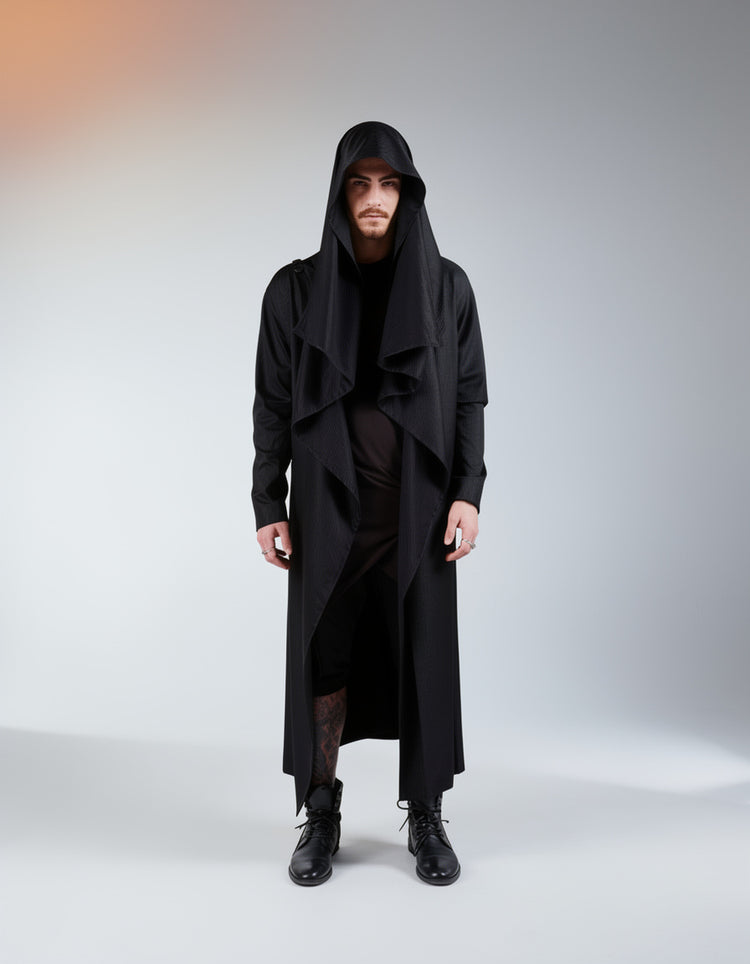 Person wearing a long black hooded coat on a gray background