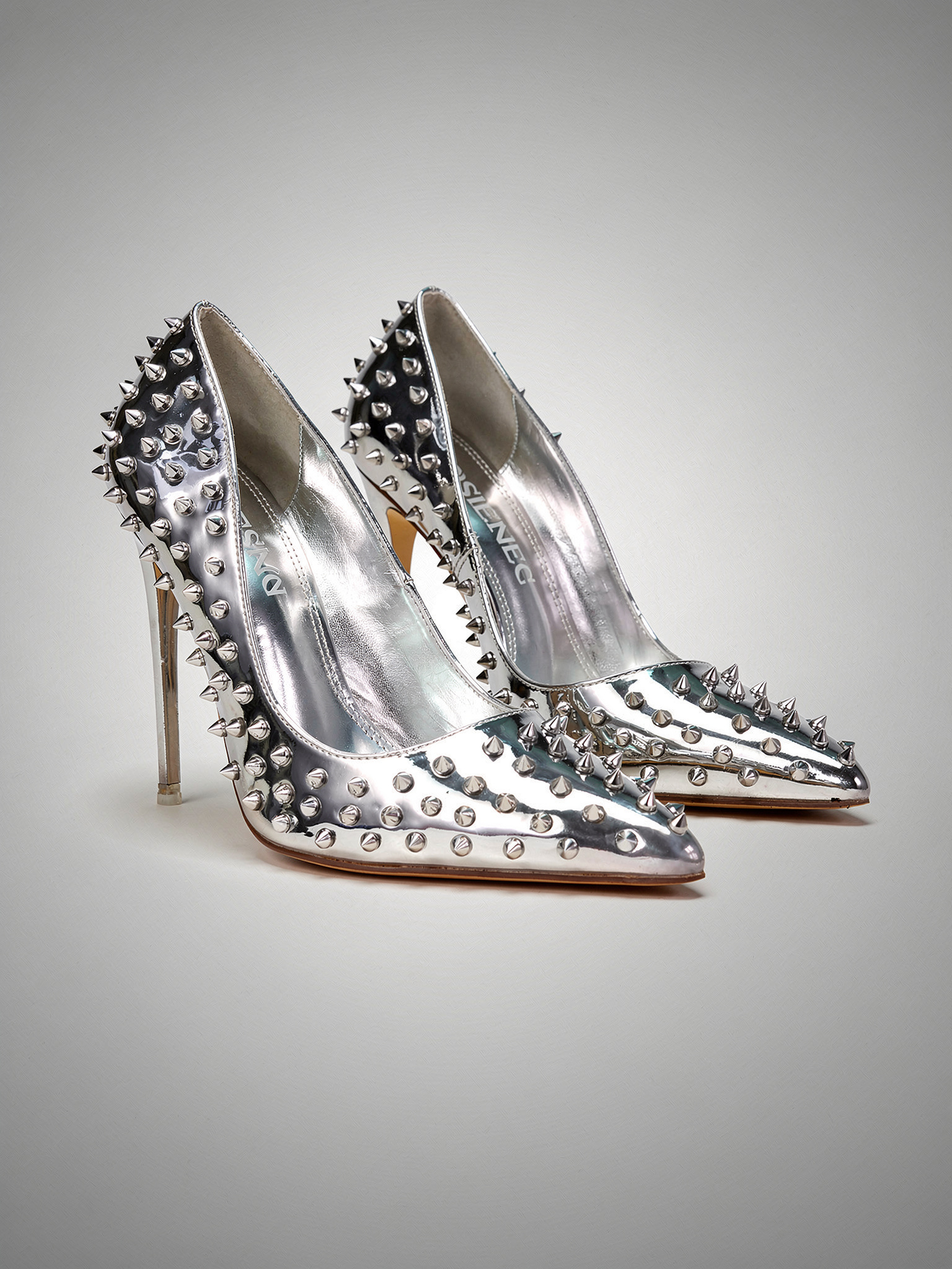 Silver studded high-heeled shoes on a gray background